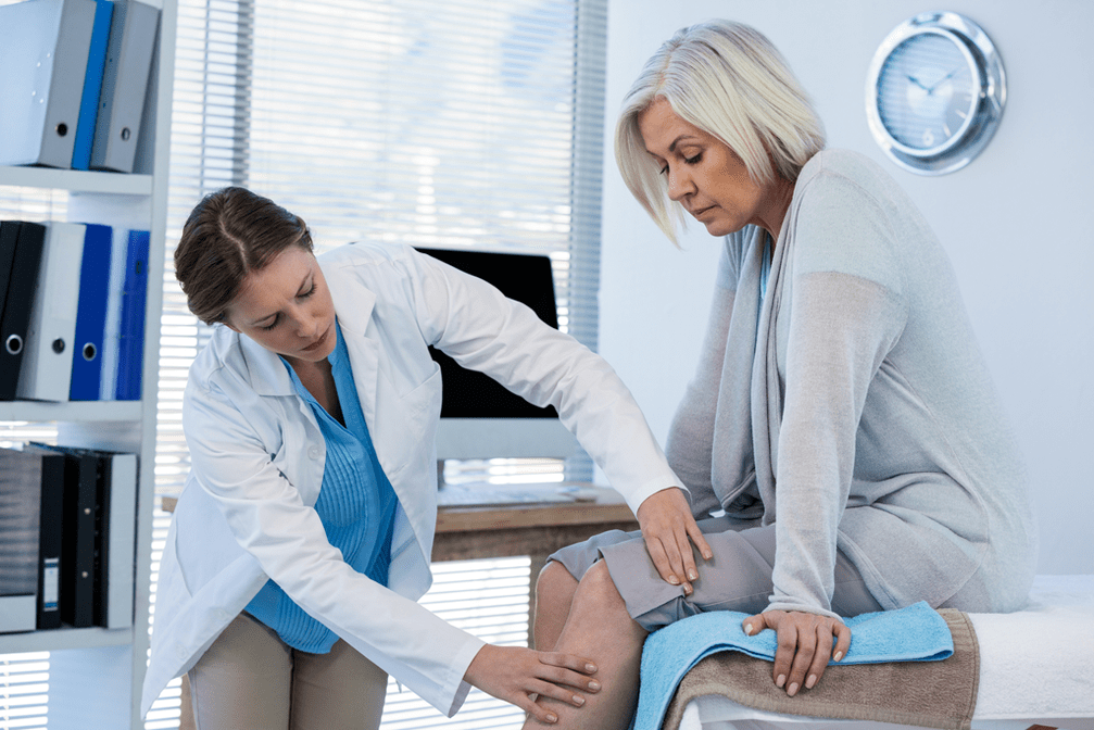 The doctor examines a patient with arthritis of the knee joint